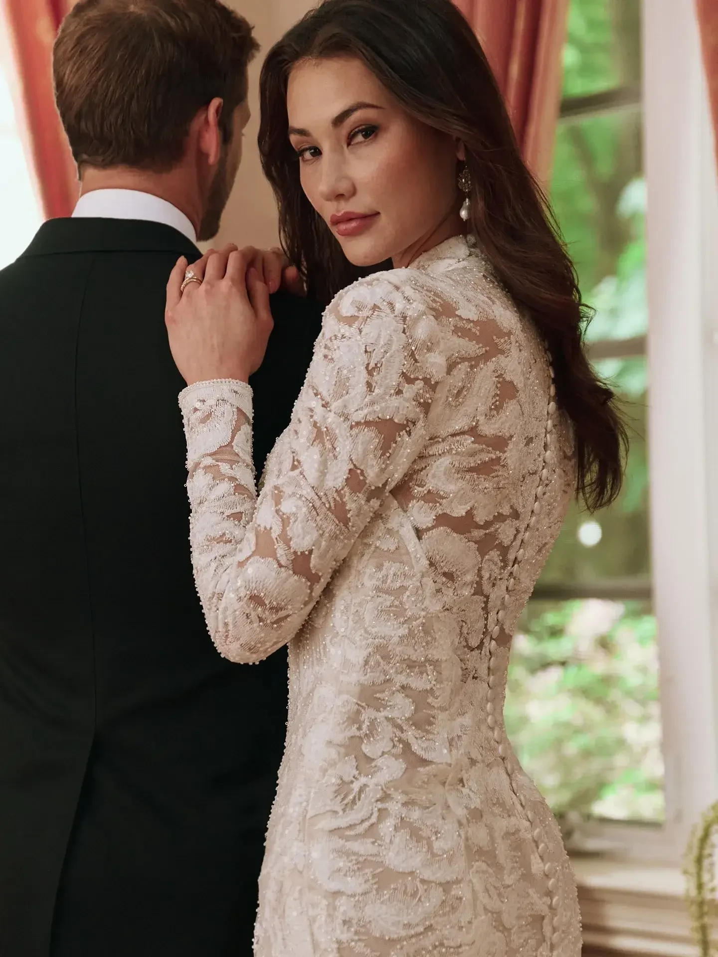 model is wearing a high neckline long sleeve sheath wedding dress