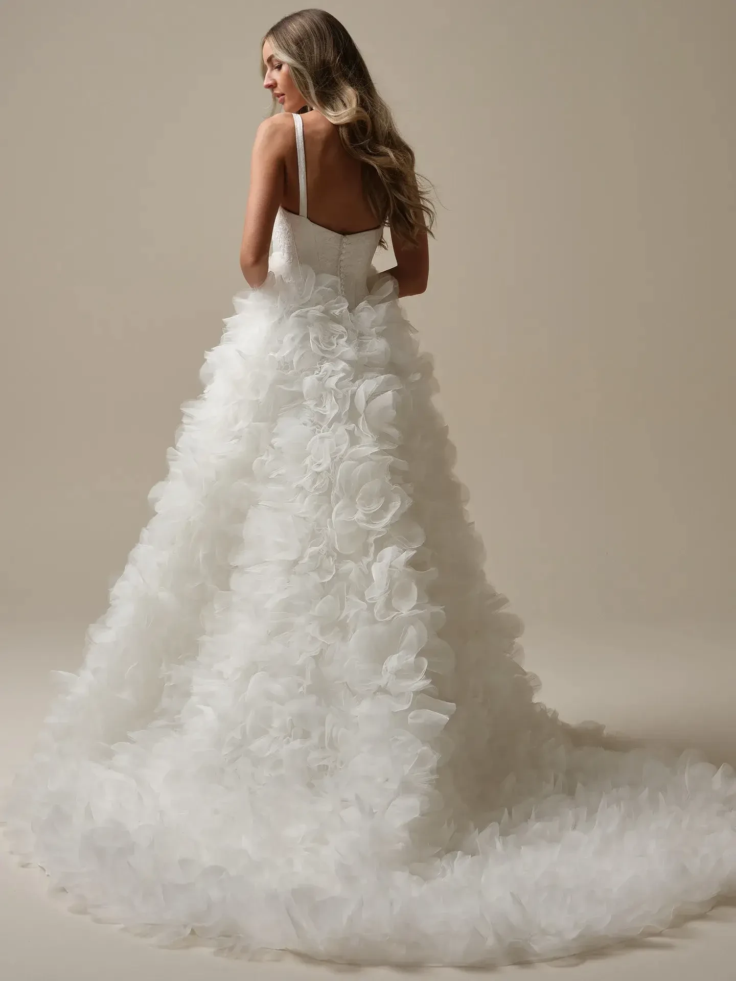 Model is wearing a ruffled jacquard wedding dress with a square neckline and full skirt