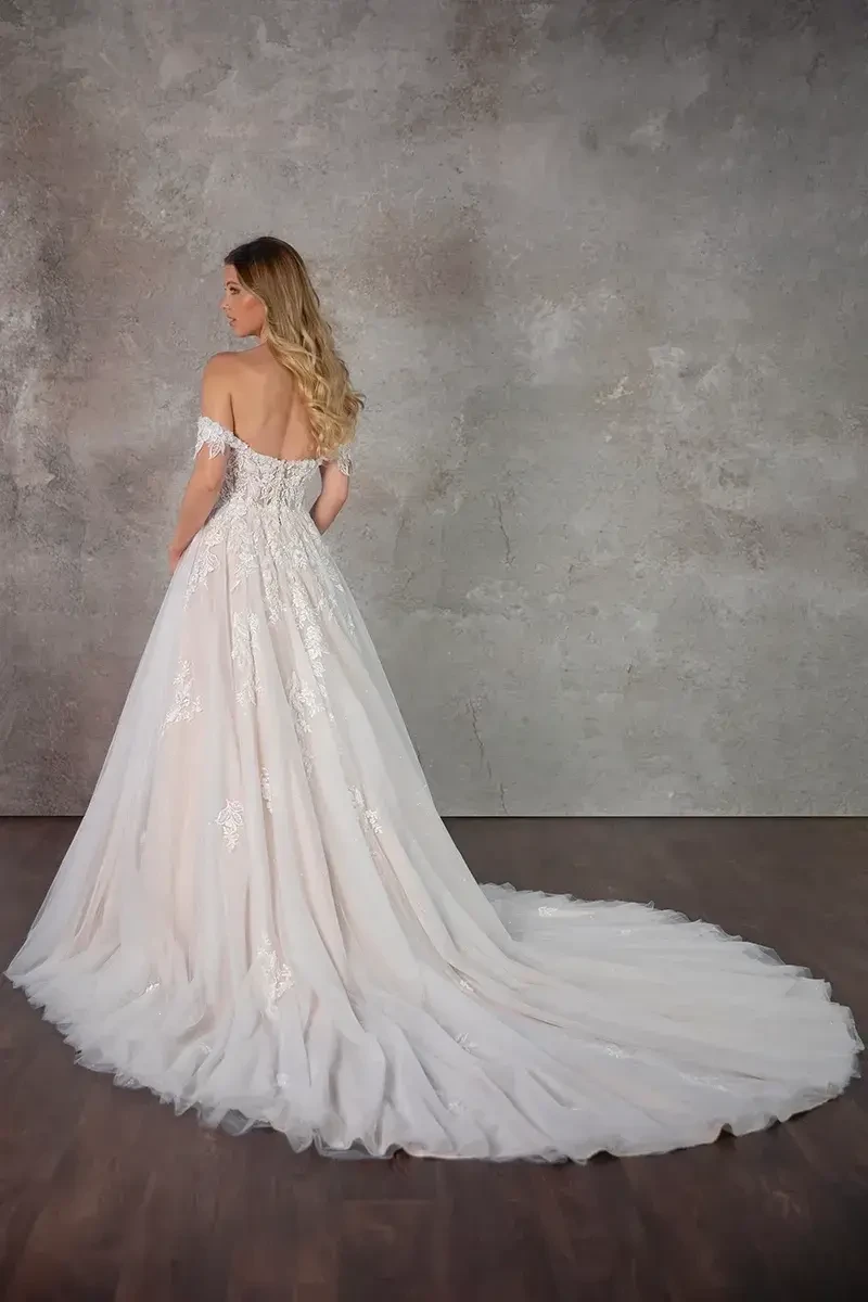 Model is wearing an a-line floral lace bridal gown with a sweetheart neckline and off the shoulder lace straps 