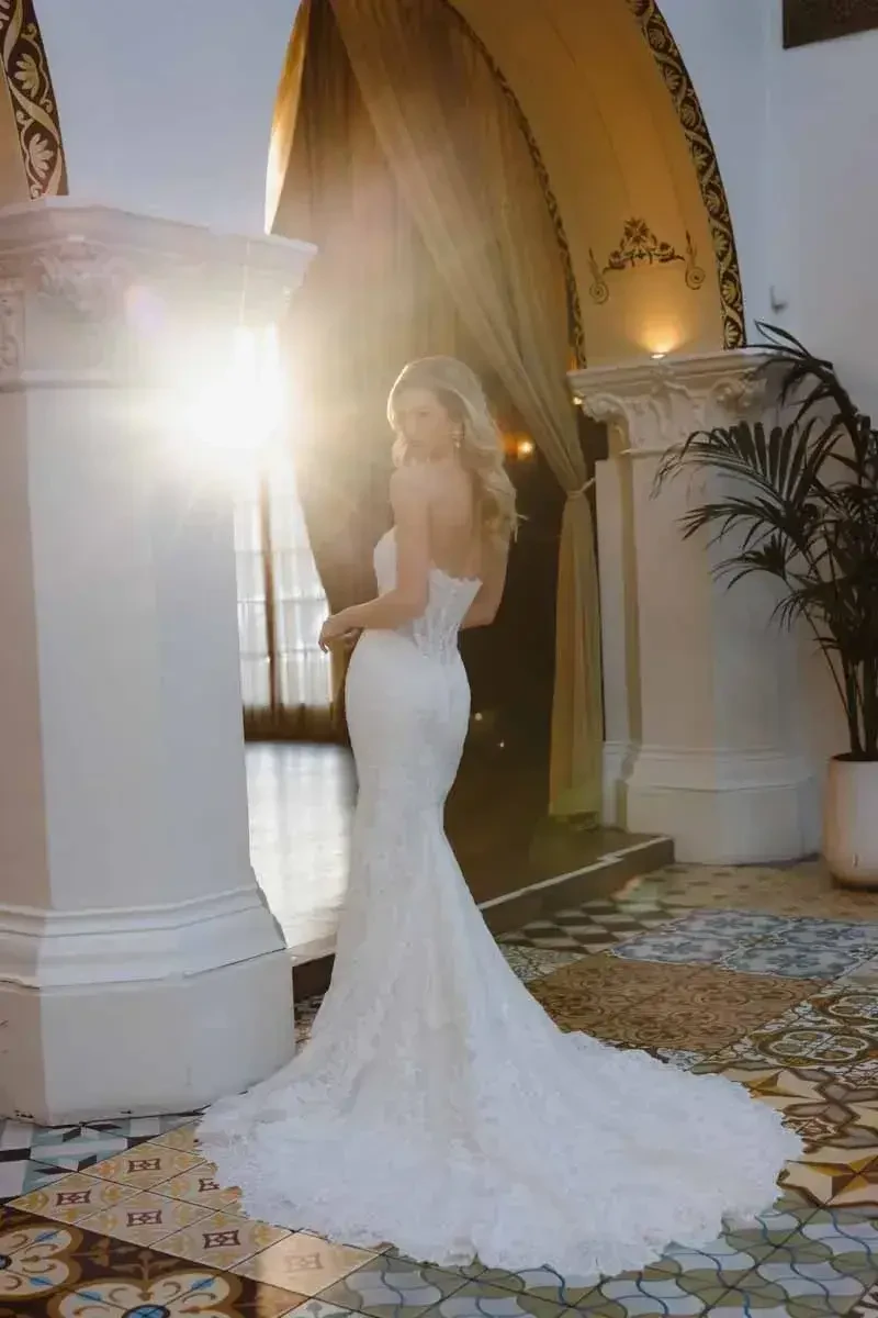 A woman in a white wedding dress stands in a beautifully lit space with elegant decor.