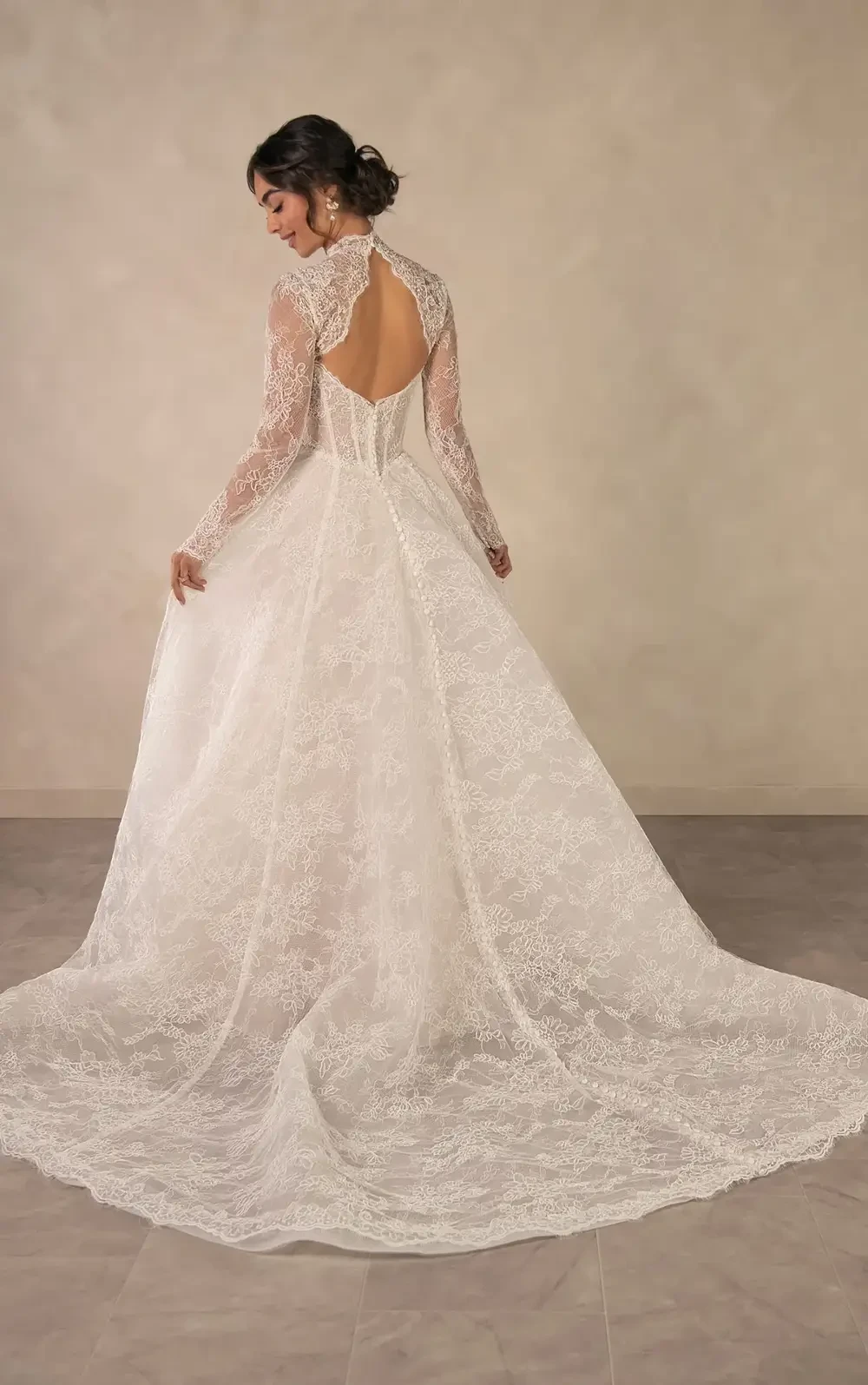 model is wearing a lace long sleeve high neckline ball gown with an open back