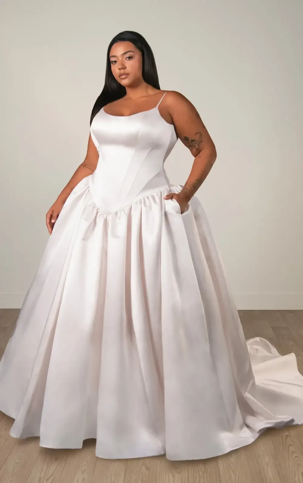 model is wearing a satin spaghetti strap a-line bridal gown with a basque waist