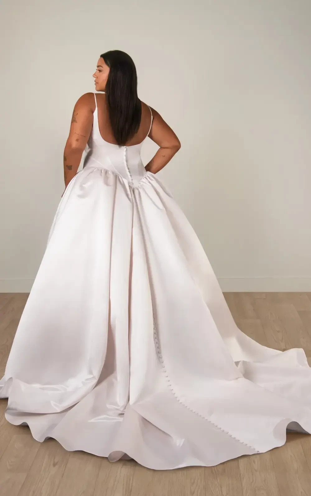 model is wearing a satin spaghetti strap a-line bridal gown with a basque waist
