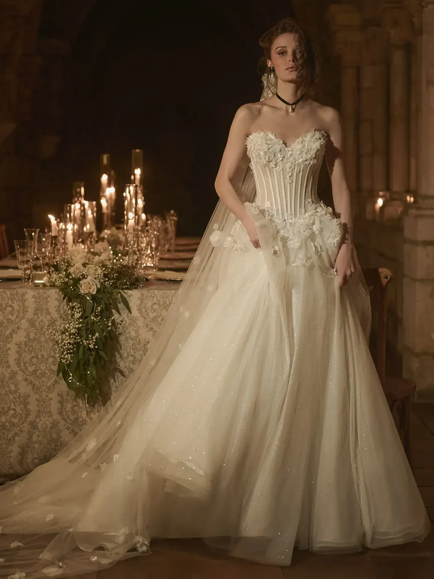 Model is wearing a 3-D floral ballgown wedding dress with exposed boning and a romantic full skirt.